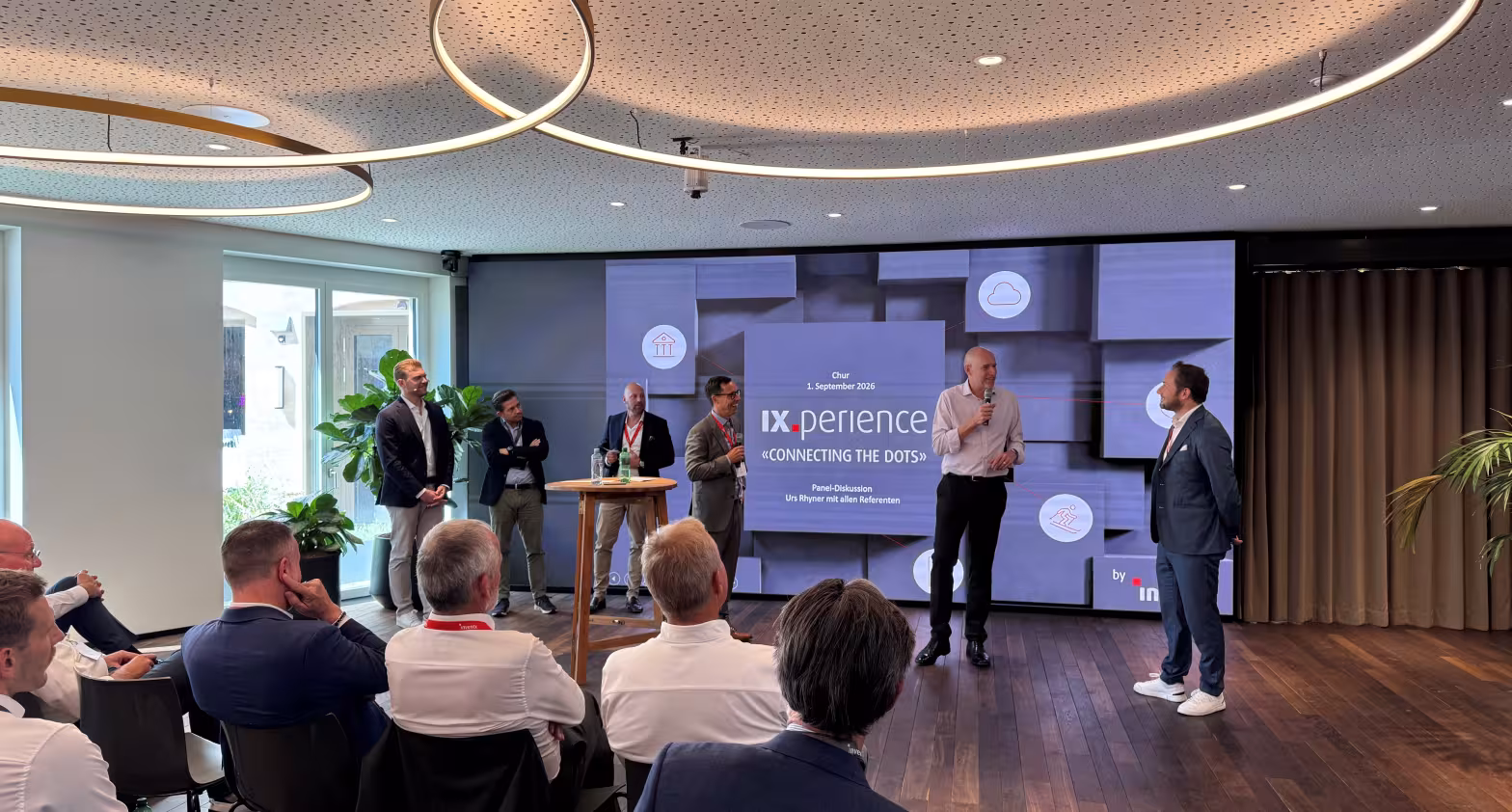 Konferenzraum mit Publikum, Rednerin präsentiert Folie auf großer Leinwand.
