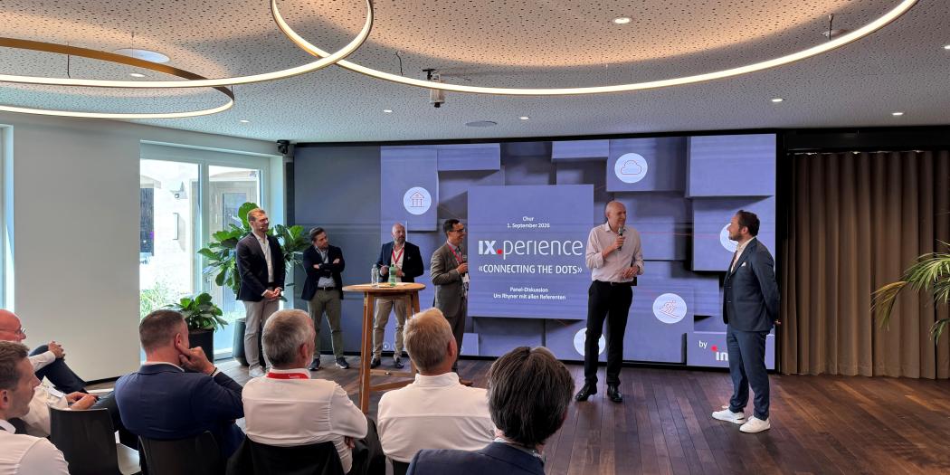 Konferenzraum mit Publikum, Rednerin präsentiert Folie auf großer Leinwand.
